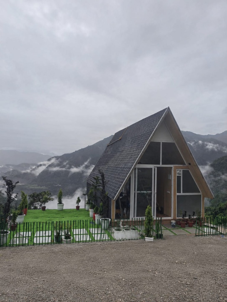 A-frame cottage glass front terrace overlooking mist-covered mountains