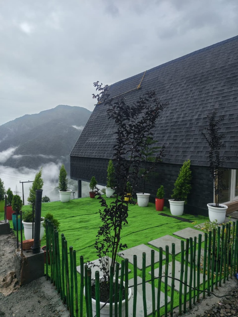 Side view of A-frame cottage dark timber roof and potted green garden terrace